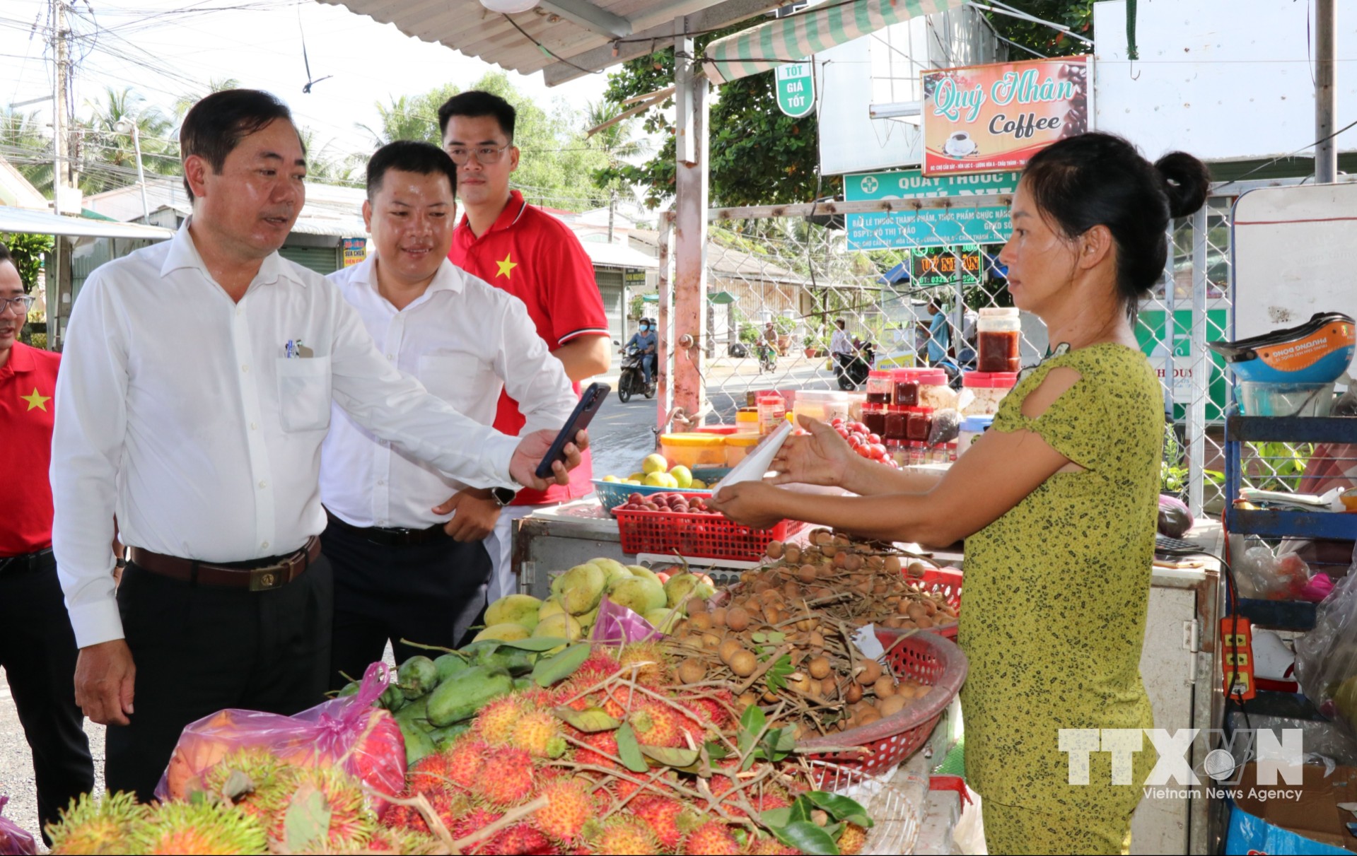 Lãnh đạo UBND xã Song Lộc, tỉnh Vĩnh Long, tuyên truyền, hướng dẫn tiểu thương sử dụng phương thức thanh toán không dùng tiền mặt. (Ảnh: Thanh Hòa/TTXVN)
